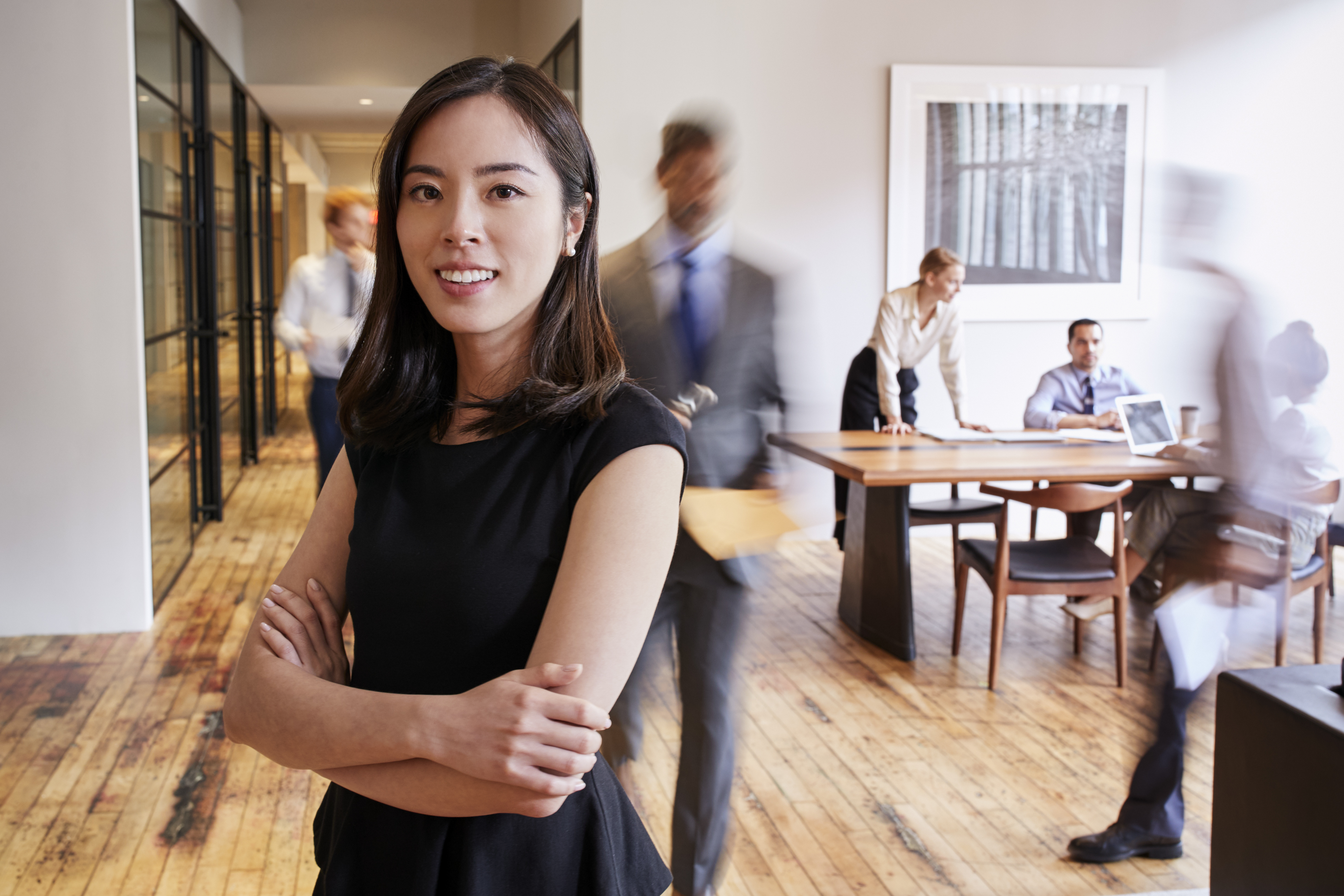 Portrait of young Asian woman in a busy modern workplace